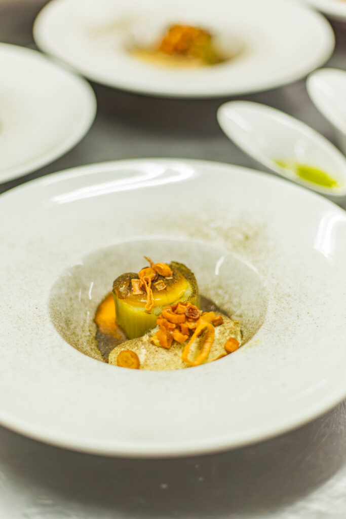 A close-up of an elegantly plated gourmet leek and potato fine dining dish prepared by CHS culinary students.