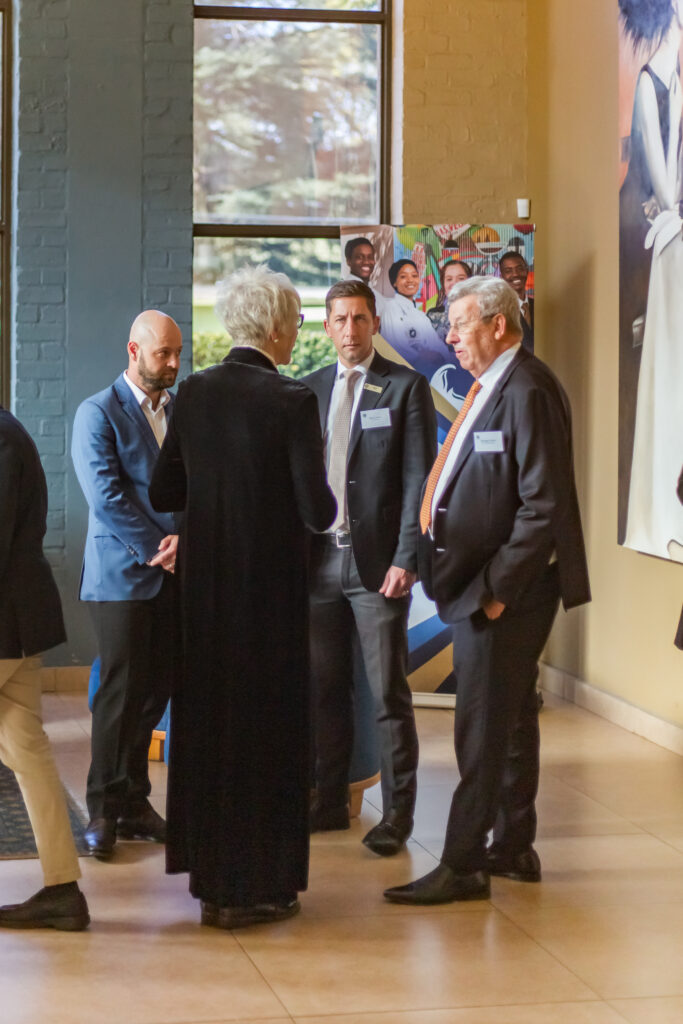 Industry professionals and general managers wearing name badges engaged in discussion inside the venue lobby.